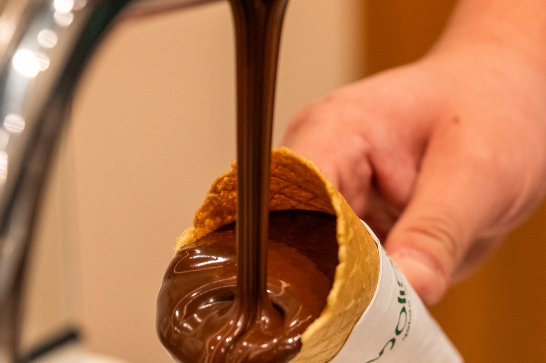 Casquinha Dimolise sendo banhada na calda de chocolate, feita na loja